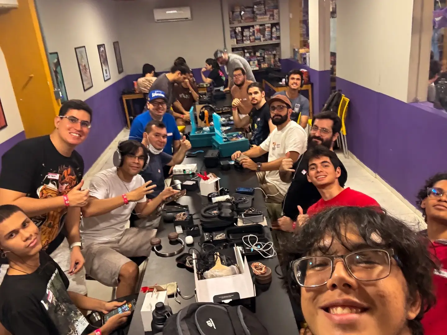 Sala cheia num encontro de audiófilos, com dezenas de fones sobre as mesas